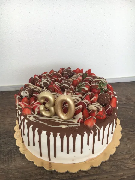 Torta s jahodami, čokoládovými guľami a zlatými sviečkami s číslom 30