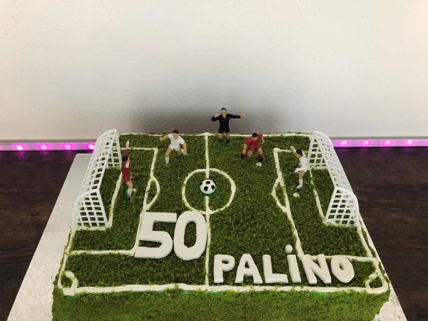Štvorcová torta v tvare futbalového ihriska s figúrkami hráčov a nápisom 50