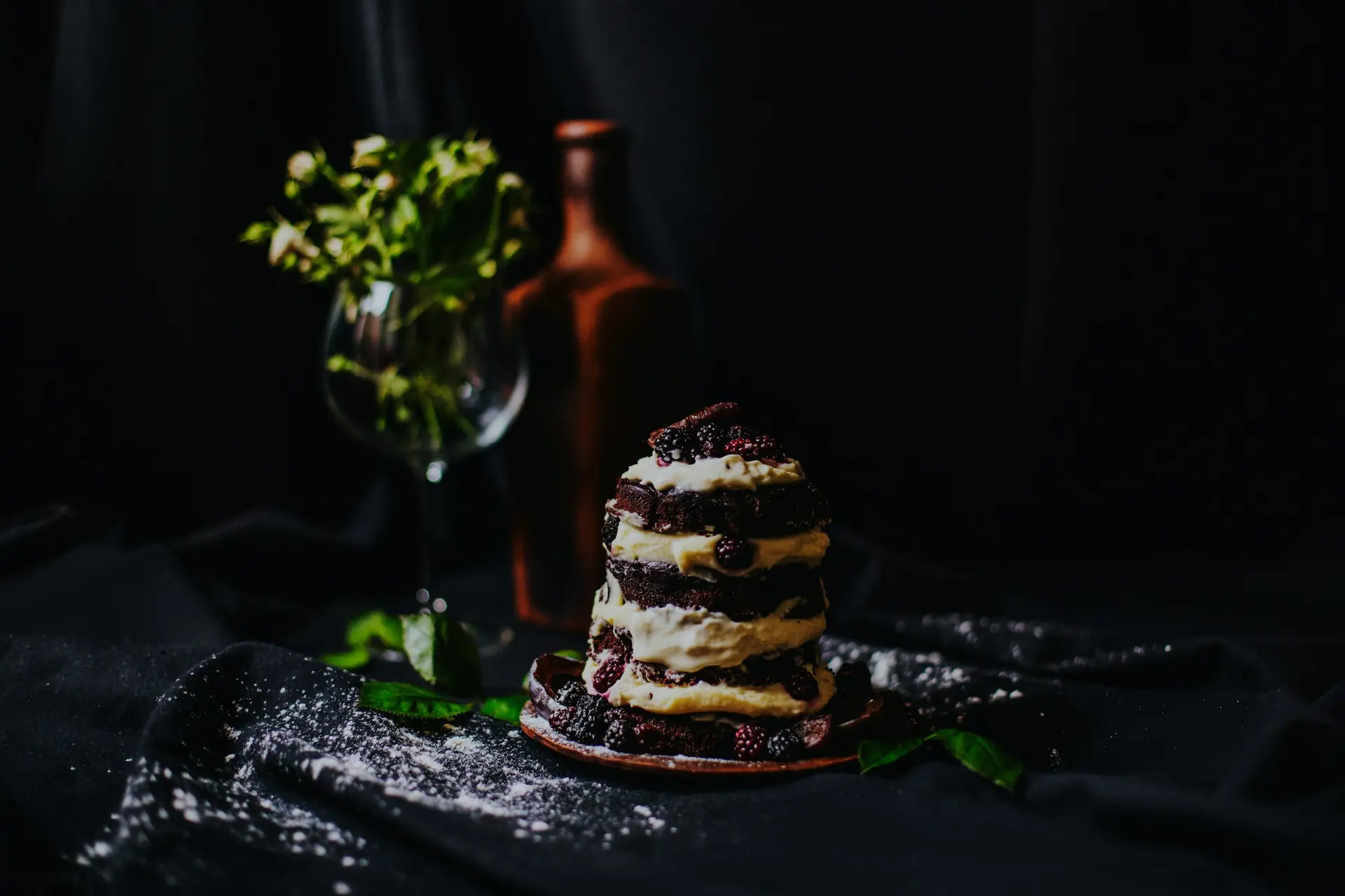 Vrstvená čokoládová torta s krémom a černicami na tmavom plátne